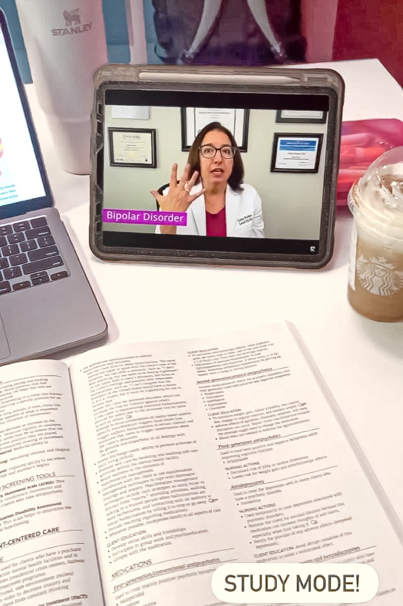 A textbook open and a Cathy Parkes RN, BSN, PHN, CWCN nursing education in Psychiatric Mental Health Nursing on Bipolar Disorder playing on an ipad