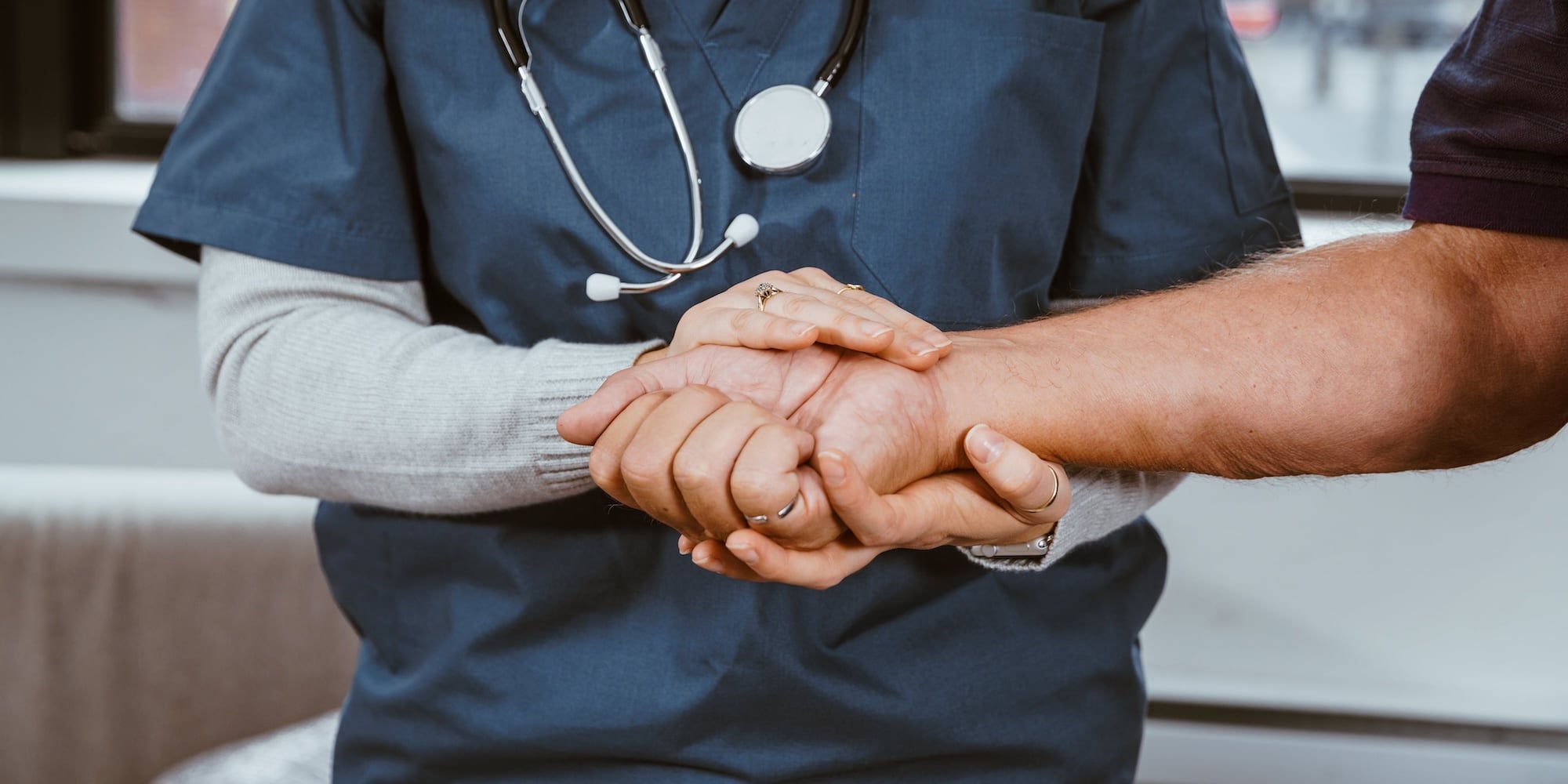 Nurse holding a patient's hand with both of her hands