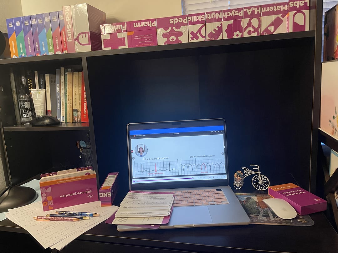 A desk showing a Cathy Parkes EKG interpretation video, EKG interpretation flashcards box open, the On-the-go flashcards box, level up nurse squad great 8, and all the rest of level up RN's flashcards